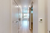 This well-designed one-bedroom, one-bathroom unit in Austin, TX (78745) offers a thoughtfully laid out single-floor plan with a clean, modern aesthetic throughout. Light wood-tone flooring flows seamlessly from room to room, complementing the crisp white walls and creating a bright, cohesive interior.

The kitchen is a functional highlight, featuring white shaker-style cabinetry, light stone countertops, a subway tile backsplash, and a full suite of stainless steel appliances including a refrigerator, electric range, over-the-range microwave, and dishwasher. A window with horizontal blinds allows natural light to fill the space, with pleasant views of the surrounding neighborhood.

A narrow hallway connects the main living area to the bedroom and bathroom, lined with white panel doors and fitted with barn-style sliding door hardware, adding a modern touch to the layout. The bedroom is a comfortable, quiet retreat featuring a high clerestory window that draws in additional natural light. A ceiling fan enhances comfort, and direct access to the bathroom adds convenience.

The bathroom is finished with warm taupe elongated subway tile surrounding a full soaking tub and shower combination, complemented by brushed nickel fixtures. The vanity area features white cabinetry with a sink and mirror, maintaining the clean, neutral palette found throughout the unit.