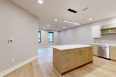 Located at 4651 Dodge St in Omaha, Nebraska, this modern 1-bedroom, 1-bathroom unit offers a thoughtfully designed open-concept layout. The combined kitchen, dining, and living area serves as the heart of the home, showcasing light hardwood flooring, recessed lighting, and a sleek linear pendant fixture. The contemporary kitchen is equipped with stainless steel appliances, a mix of white upper cabinets and warm wood lower cabinetry, a tile backsplash, and a generously sized island with a crisp white countertop — ideal for both meal preparation and casual dining. Large black-framed windows allow natural light to fill the living area, providing views of the surrounding neighborhood. The bedroom features soft carpeting, a ceiling fan, and its own set of black-framed windows that continue the modern aesthetic. The bathroom is outfitted with a full tub-shower combination and brushed nickel fixtures. Three closets provide ample storage throughout the unit, including a dedicated laundry closet with a stacked full-size washer and dryer. Neutral gray tones and clean white trim unify the interior, creating a cohesive, modern ambiance throughout this well-appointed Omaha residence.