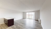 Located at 801 Cooper Landing Rd in Cherry Hill, NJ, this single-floor unit offers a clean, modern aesthetic with a thoughtfully designed open-concept layout. The spacious living area is finished with light gray laminate hardwood flooring and bright white walls, creating an airy and inviting atmosphere. Large sliding glass doors lead to a private balcony, flooding the living space with natural light and providing outdoor views of the surrounding neighborhood.

The kitchen is seamlessly integrated into the living space via a peninsula with a marble-style countertop and rich dark-wood cabinetry. It features stainless steel appliances including a gas range, microwave, and refrigerator, complemented by a white subway tile backsplash that adds a contemporary touch.

The bedroom is generously sized with plush carpeting, dual sliding-door closets offering ample storage, and its own sliding glass door opening to a balcony. An additional carpeted room provides flexible living space.

The bathroom is elegantly appointed with a tiled tub-and-shower combination featuring a decorative mosaic accent border, a floating wood-grain vanity with an integrated white basin sink, and a framed mirror, all contributing to a polished, updated feel throughout the unit.
