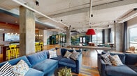 Located at 241 Shadowline Dr in Boone, NC, this expansive single-floor amenity space blends industrial design with lively, nature-inspired décor. The open floor plan is defined by exposed concrete columns, visible ductwork, and high ceilings that create an airy, loft-like atmosphere. Warm hardwood flooring flows throughout, unifying the various activity zones seamlessly.

The lounge area features plush navy sectional sofas arranged around coffee tables, accented by colorful throw pillows and a bold red pendant light. Large windows along the perimeter flood the space with natural light and frame scenic views of the surrounding Blue Ridge Mountains. A vibrant teal accent wall with curated artwork adds a pop of color to the sitting area.

A dedicated game zone includes a full-size pool table set atop a multicolored area rug, complemented by high-top tables and teal metal barstools. Striking hand-painted landscape murals depicting mountain scenery wrap across several walls, reinforcing the connection to the Appalachian setting.

A communal bar-height table lined with yellow metal chairs sits beneath statement pendant lighting near a wood-paneled feature wall with a mounted flat-screen TV. The coffee bar area showcases a bold, textured accent wall and a generous counter equipped with beverage stations. A glass-enclosed study or meeting room is accessible from the main floor, offering a quieter workspace within the larger social environment.
