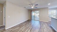 Located at 4129 Hearthside Dr in Wilmington, NC, this 2-bedroom, 1-bathroom residence offers a well-designed single-floor layout with a cohesive, neutral color palette throughout. The open-concept living, dining, and kitchen area serves as the heart of the home, featuring wood-look luxury vinyl plank flooring and a ceiling fan with light fixture. Sliding glass doors lead to a private balcony, allowing natural light to fill the space and providing pleasant outdoor views. The kitchen is equipped with stainless steel appliances, including a refrigerator, range, and dishwasher, complemented by white shaker-style cabinetry, granite-look countertops, and a functional window above the sink. The bathroom features a white vanity with a clean quartz countertop, an undermount sink, brushed nickel fixtures, and a framed mirror, with direct access to a walk-in closet outfitted with wire shelving. Both bedrooms are carpeted and include ceiling fans; the primary bedroom offers sliding balcony access and a generous walk-in closet. Additional spaces include a laundry area, utility room, and multiple closets for storage. The textured ceilings and warm, neutral tones throughout lend the space a clean, move-in-ready appeal.