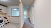 Located at 55 Regina Figure Eight in East Windsor, Connecticut, this single-floor unit offers a practical and well-organized layout designed for comfortable everyday living. A central hallway connects the various rooms, with light-toned walls and a mix of carpet and tile flooring throughout.

The spacious living area is carpeted and bathed in natural light from a large multi-pane window, creating a bright and open atmosphere. An adjacent room, also carpeted with its own window overlooking lush greenery, serves well as a bedroom or flexible-use space.

The kitchen is efficiently laid out in an L-shape, featuring white cabinetry with wood-trimmed accents, light countertops, tile flooring, and a full suite of white appliances including a refrigerator, electric range, and dishwasher. A window above the sink allows natural light to fill the space.

Two bathrooms serve the unit. One includes a vanity with wood-trimmed cabinetry, a large mirror, tile flooring, and a shower enclosure. The second bathroom mirrors a similar clean, functional aesthetic with tile flooring and a vanity with ample counter space.

Throughout the unit, neutral tones and clean lines create a calm, move-in-ready environment. The floor plan is thoughtfully arranged to maximize both privacy and flow between living, dining, and sleeping areas.