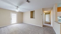 This single-story 2-bedroom, 2-bathroom home offers a thoughtfully arranged floor plan designed for comfortable everyday living. The spacious living room serves as the heart of the home, featuring warm neutral-toned walls, plush carpeting, a ceiling fan with light fixture, and a sliding glass door that allows natural light to fill the space. A built-in pass-through opening connects the living room to the kitchen, creating an open and communicative flow between the two areas. The kitchen is efficiently designed with warm wood-toned cabinetry, granite-style countertops, white appliances including a range, dishwasher, refrigerator, and microwave, along with durable wood-look vinyl flooring. Both bedrooms are generously proportioned, featuring plush carpet, ceiling fans, and neutral paint tones. The primary bedroom is notably spacious and includes closet access. Both bathrooms are finished with wood-look vinyl flooring, warm wood vanity cabinetry, granite-style countertops, and a tub-shower combination. Clean white trim and consistent neutral tones carry throughout the entire home, contributing to a cohesive and inviting atmosphere that is move-in ready.