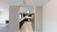 This single-floor residence offers a clean, modern interior designed for comfortable everyday living. The kitchen serves as a functional centerpiece, showcasing rich dark cabinetry that contrasts beautifully with light granite-style countertops. Stainless steel appliances — including a refrigerator, electric range, and dishwasher — are complemented by large-format tile flooring and ample upper and lower cabinet storage. Overhead fluorescent lighting ensures the workspace remains bright and practical throughout the day.

The bedrooms are generously sized, finished with soft wall-to-wall carpeting and neutral warm-toned walls. Each room benefits from natural light through well-placed windows offering outdoor views, and ceiling fans provide year-round comfort. Walk-in or reach-in closets offer convenient storage solutions.

The bathrooms maintain a consistent design language with the rest of the home, featuring dark vanity cabinetry topped with light granite-style counters, undermount sinks, and stylish multi-globe light fixtures above large mirrors. Tile flooring ties the aesthetic together neatly.

Throughout the space, a cohesive neutral color palette, clean lines, and consistent material choices create a calm, move-in-ready atmosphere that balances practicality with modern style.
