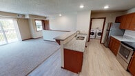 This single-floor residence offers a thoughtfully designed layout that balances open living areas with functional private spaces. The kitchen serves as a central hub, featuring rich medium-toned wood cabinetry, granite countertops, and stainless steel appliances including an electric range and refrigerator. A peninsula with a double sink and additional granite surface provides both prep space and a casual dining option. Light wood-look flooring runs throughout the kitchen and connects seamlessly to a dedicated laundry area, which accommodates a full-size washer and dryer. The open floor plan transitions into a carpeted living area, which benefits from natural light through a window overlooking the surrounding neighborhood. Bedrooms are generously sized, each featuring plush carpet, ceiling fans, and natural light. Closets with built-in shelving and hanging systems provide ample storage. Two bathrooms serve the unit; one includes a shower-tub combination with a dark-cabineted vanity and overhead wall storage, while the second features a walk-in shower stall with the same dark vanity style and tile-look flooring. Textured ceilings and warm wood-toned door trim carry throughout, lending a cohesive and comfortable character to the entire space.