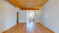 This thoughtfully designed 4-floor home blends modern aesthetics with warm natural materials throughout. Signature tongue-and-groove wood ceilings span multiple levels, complemented by light hardwood floors that create a cohesive, inviting atmosphere. The open living areas are bright and airy, benefiting from abundant natural light streaming through large multi-pane windows dressed with sheer curtains.

The well-appointed kitchen is a standout feature, showcasing white shaker cabinetry with matte black hardware, a large central island with quartz countertops, a subway tile backsplash, and a full suite of stainless steel appliances including a professional double oven range and French door refrigerator. Pendant lighting adds a modern finishing touch.

Bedrooms are carpeted for comfort and feature the same distinctive wood ceilings, along with generous windows that bring in natural light. The bathrooms are elegantly finished with hexagonal tile flooring in soft grey tones, white vanities topped with quartz, and brushed brass fixtures and mirrors that lend a sophisticated, contemporary feel. Glass-enclosed showers with white subway tile complete the refined look.

A staircase with warm wood treads connects the multiple floors, and an attached garage with concrete flooring and an electrical panel provides practical convenience.