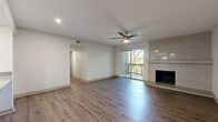 This two-bedroom, two-bathroom residence in Austin, TX offers a well-designed single-level layout with wood-style flooring that flows consistently throughout the home. The living room serves as the heart of the space, anchored by a tile-surround fireplace and a ceiling fan, and opens directly to a private patio through sliding glass doors that invite natural light and outdoor views. Adjacent to the living area, the kitchen features gray cabinetry, gray countertops, a diamond-patterned tile backsplash, stainless steel appliances including a range and dishwasher, and a skylight that brightens the space. A pass-through connects the kitchen to the living area, enhancing the open feel. The primary bedroom is generously sized, offering a ceiling fan, a sliding glass door to a balcony, and a dedicated walk-in closet with built-in shelving. The second bedroom also includes a ceiling fan and its own walk-in closet with matching built-in storage. Both bathrooms are cleanly finished, with one featuring a tub-shower combination with floor-to-ceiling tile surround and brushed nickel fixtures. Additional storage is provided through four closets and a pantry, ensuring exceptional functionality throughout this thoughtfully appointed Austin home.