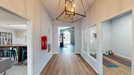Located at 101 Royal Dr in Madison, Alabama, this single-story amenity facility offers a thoughtfully designed layout spanning a generous floor area across six distinct spaces. The entrance corridor makes an immediate impression with its soaring ceilings, warm wood-look flooring, and a striking geometric brass chandelier that sets an upscale tone throughout.

The fitness center is a standout feature, boasting vaulted ceilings, arched windows that flood the space with natural light, and a distinctive shiplap accent wall. It is fully equipped with cardio machines including treadmills, ellipticals, and a rowing machine, as well as a multi-station cable system, free weights, and a weight bench. A ceiling fan ensures comfortable airflow during workouts.

Adjacent to the gym is a dedicated yoga or studio room, visible through interior windows from the hallway, providing a quiet space for stretching or group classes. A wall-mounted TV and open floor area make it versatile for various activities.

The lounge area offers a welcoming, residential feel with comfortable gray sofas, colorful accent pillows, framed artwork, and abundant natural light from multiple windows. A pet grooming room rounds out the amenities, equipped with a stainless steel grooming tub, a grooming table, and playful pet-themed wall art. Throughout, consistent wood-look flooring and a neutral color palette create a cohesive and polished environment.