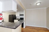 Located at 15530 Ella Blvd in Houston, TX, this single-floor, one-bedroom, one-bathroom residence offers a practical and well-organized layout. The entrance leads into a combined dining, kitchen, and living area that maximizes the available space. The kitchen is designed in a galley style, featuring dark granite-style countertops, white cabinetry, black appliances including a refrigerator and electric range, a built-in sink, and warm hardwood-style flooring. A peninsula counter opens toward the living and dining area, enhancing the open-concept feel. The living area is finished with plush carpeting, crown molding, and a sliding glass door with vertical blinds that allows natural light and provides access to an outdoor area. The bedroom is a comfortable size, carpeted, and features a window with views of surrounding greenery, a closet, and access to additional storage. The bathroom includes a tub-shower combination, a toilet, over-toilet cabinetry for extra storage, and hardwood-style flooring. A dedicated pantry provides convenient additional storage. Neutral wall tones throughout create a clean, cohesive aesthetic across the entire unit.