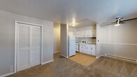 Located at 3761 S State Ave in Indianapolis, Indiana, this one-bedroom, one-bathroom unit offers a practical and efficiently organized single-floor layout. The open-concept living and dining area flows seamlessly into the kitchen, which features white cabinetry, a white refrigerator, a range, and a microwave set against light hardwood-style flooring. The transition from the kitchen's hard flooring to the neutral-toned carpeting in the living area creates a clear delineation between spaces. A louvered bi-fold closet door adds a classic touch to the living area, providing convenient storage. The bedroom is a comfortable size, featuring carpet flooring, a window that brings in natural light, a wall-mounted air conditioning unit, and a baseboard heater. A dedicated closet with a hanging rod and shelf offers organized storage. The unit includes three closets in total, providing ample storage throughout. The bathroom features a full tub and shower combination with white subway-style tile surround. Neutral gray walls and white trim run consistently throughout, giving the space a clean, cohesive aesthetic. The entry area also features a window and baseboard heating, completing this well-organized and functional unit.