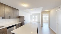 Located at 7711 MacLeod Trail SW in Calgary, this one-bedroom, one-bathroom unit offers a thoughtfully designed layout that makes efficient use of its cozy footprint. The contemporary interior is finished with light wood-look flooring throughout, creating a warm and cohesive aesthetic across all rooms.

The kitchen is a standout feature, outfitted with rich dark wood cabinetry extending to the ceiling for ample storage, crisp white quartz countertops, a classic subway tile backsplash, and a full suite of stainless steel appliances including a refrigerator, electric range, built-in microwave, and dishwasher. A peninsula counter provides additional prep space and casual seating potential.

The bathroom continues the modern theme with a wood-toned vanity topped with a white countertop, a large mirror, pendant lighting, and a full tub-shower combination framed by clean tile surround.

The bedroom is a comfortable, well-proportioned retreat featuring a large window that fills the room with natural light and offers views of the surrounding Calgary cityscape and greenery beyond.

A private balcony with glass-panel railing extends the living space outdoors, providing open views of MacLeod Trail and the broader neighbourhood under Calgary's expansive skies.