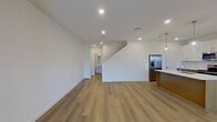 Located at 3412 Oxenfree Blvd in Rowlett, TX, this modern two-story home offers 1,640 square feet of well-designed living space across four bedrooms and four bathrooms. The ground floor spans 670 square feet and features an open-concept kitchen and living area with light wood-look flooring throughout. The kitchen is a standout, boasting a large center island with a white quartz countertop, a dual-tone design pairing white upper cabinetry with warm wood-grain lower cabinets, stainless steel appliances including a French door refrigerator, and sleek pendant lighting overhead. A convenient half bath with a pedestal sink is also located on this floor. The upper level covers 970 square feet and hosts all four bedrooms, including a spacious 400-square-foot primary suite with an ensuite bath featuring a wood-grain vanity and white countertop. Secondary bedrooms are carpeted, each equipped with a ceiling fan, natural light from windows with exterior views, and closet space. Bathrooms throughout maintain a clean, modern aesthetic with wood-toned cabinetry and minimalist fixtures. The home's crisp white walls, recessed lighting, and consistent use of light wood flooring create a bright, cohesive ambiance throughout.