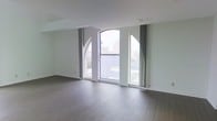 This multi-floor space spans three levels and showcases a blend of architectural character and modern finishes. One of its most distinguishing features is the series of arched windows that frame sweeping urban views, flooding the interiors with natural light and creating an airy, open ambiance. The wide-plank hardwood flooring runs throughout, adding warmth and continuity to the clean, neutral palette of white and light gray walls. The vaulted ceiling lines follow the graceful curves of the arched windows, lending the space a sense of grandeur and volume without feeling overwhelming. The elevated positioning of the upper floors provides expansive sightlines across the surrounding cityscape, making natural light a defining characteristic at every level. The overall design sensibility is minimal and uncluttered, allowing the architectural details — particularly the arched window casings and the interplay of light and shadow — to take center stage. Curtain panels flanking the windows offer both a soft textural contrast and functional light control. The result is a cohesive, well-lit space that balances distinctive architectural elements with a versatile, move-in-ready interior across all three floors.