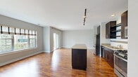 This 2-bedroom, 2-bathroom residence offers a thoughtfully designed single-floor layout that balances comfort and functionality. The open-concept kitchen and living area serves as the heart of the home, featuring rich hardwood-style flooring that runs throughout. The kitchen is outfitted with dark espresso cabinetry, granite countertops, a full suite of stainless steel appliances including a refrigerator, gas range, microwave, and dishwasher, and a central island with additional storage and prep space. Track lighting overhead adds both style and practicality. The living area is bright and airy, benefiting from natural light through large windows and a sliding glass door that opens to a private balcony overlooking a landscaped courtyard and multi-story residential exterior. Both bedrooms are carpeted and generously sized, with the primary bedroom offering notable square footage, built-in closet storage, and a calm, neutral palette. The second bedroom features adjustable shelving built into the closet area. The bathrooms include a tub-shower combination with clean white tile accented by a dark horizontal border. Neutral gray walls throughout create a cohesive, modern aesthetic across the entire residence.