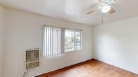 Located on E Olympic Blvd in East Los Angeles, this single-floor, one-bedroom, one-bathroom unit offers a thoughtfully utilized compact layout. The main living area features warm wood-look flooring that runs throughout the space, crisp white walls, and a ceiling fan with integrated lighting, contributing to a clean and functional ambiance. A wall-mounted heating unit provides climate control, while a large window fitted with vertical blinds admits generous natural light and offers street-facing views of the surrounding neighborhood.

The kitchen is positioned adjacent to the main living area and is outfitted with white cabinetry, a gas range with overhead ventilation, and a stainless steel double-basin sink. The standout feature is the granite-style countertop with bold veining, adding a refined touch to the utilitarian space. A window above the sink brings in additional natural light and outdoor views. A full-size refrigerator is also included.

The bedroom is a generously proportioned room relative to the overall footprint, with the same wood-look flooring, white walls, a ceiling fan, a wall-mounted heating unit, and a large window with vertical blinds offering neighborhood views.

The bathroom is compact and efficiently designed, finished in white throughout, with a sink, toilet, and a mirrored medicine cabinet.