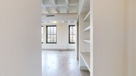 This one-bedroom, two-bathroom loft in Memphis, TN blends industrial character with modern finishes across a thoughtfully laid-out single floor. The open living area is defined by striking exposed beam ceilings with visible ductwork painted white, polished concrete floors, and large black-framed windows that flood the space with natural light and frame views of the surrounding cityscape. Built-in shelving adds functional storage and architectural interest to the main living area.

The kitchen is well-appointed with a contrast of dark upper cabinetry and crisp white lower cabinets, light quartz countertops, a tile backsplash, white appliances, and a center island with pendant lighting overhead — ideal for both cooking and casual dining.

The bedroom continues the loft aesthetic with exposed brick walls, concrete floors, and generous window views of neighboring architecture. A spacious walk-in closet with wire shelving and built-in shelving units offers ample storage.

The bathroom is cleanly finished with a single-sink vanity, light quartz countertop, tile flooring, and a glass-enclosed walk-in shower adorned with soft blue subway tiles and chrome fixtures. The entrance provides a welcoming transition into the home, completing this well-designed urban retreat.