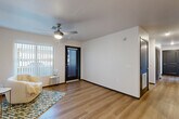 Located at 6775 N 67th Ave in Glendale, Arizona, this single-story, 3-bedroom, 2-bathroom residence offers a clean, modern aesthetic with consistent wood-look flooring and crisp white walls throughout. The living room welcomes you with a ceiling fan, natural light from a large window with vertical blinds, and direct access through a sleek dark-framed front door. The kitchen is a functional highlight, featuring warm wood-tone cabinetry with brushed metal hardware, light countertops, and a full suite of white appliances including a range, microwave, dishwasher, and refrigerator — all set atop the same light-toned flooring. Each of the three bedrooms is equipped with a ceiling fan and window, offering natural light and comfortable ventilation. The primary bedroom provides a generous footprint with ample wall space. Both bathrooms continue the home's modern design language, with one notably featuring ADA-compliant accessibility elements including grab bars near the shower and toilet, a spacious open layout, and a wood-finish vanity. Dark-painted interior doors with raised panel detailing add a contemporary contrast to the bright, neutral interiors, creating a cohesive and polished living environment throughout.