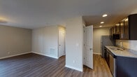 Located in Jeffersonville, Indiana, this well-appointed single-floor residence offers a clean, modern aesthetic throughout. Rich, dark wood-look flooring flows consistently across the open living areas and bedrooms, complemented by neutral-toned walls and crisp white trim that create a bright, cohesive atmosphere. The spacious living area is generously proportioned, bathed in natural light, and features direct access to a private balcony through glass doors — an ideal spot for enjoying outdoor views. The kitchen is thoughtfully designed with dark espresso-toned cabinetry, light granite countertops offering ample prep space, and stainless steel appliances including a full-size refrigerator and range. Recessed lighting adds a polished touch to the kitchen area. The bedrooms are comfortably sized, each featuring wood-look flooring and windows fitted with blinds that allow for controlled natural light. The bathrooms are finished with matching dark vanity cabinetry, granite countertops, and clean white fixtures. One bathroom includes a full tub-shower combination, while the other features a well-lit vanity with a large mirror. Throughout the unit, the design strikes a balance between contemporary style and functional comfort, making it a move-in-ready residence in the Jeffersonville area.
