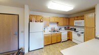 This single-floor residence offers a practical and comfortable layout with clearly defined living spaces. The kitchen is well-equipped, featuring warm honey-toned wood cabinetry that extends to the ceiling for ample storage, light-colored countertops, a double sink, and white appliances including a refrigerator, dishwasher, stove, and built-in microwave. Tile flooring adds durability to this functional cooking space, which is illuminated by a large overhead fluorescent light fixture.

The living area is carpeted and open in feel, with neutral white walls that lend a clean, airy atmosphere. A window allows natural light to filter in, making the space feel welcoming. The room offers generous wall space, providing flexibility for furniture arrangement.

The bedroom is carpeted and features a large window with blinds that brings in natural light and offers exterior views. A built-in closet with a wood-panel door provides convenient storage, and the room's neutral tones create a calm, restful environment.

The bathroom is finished with tile flooring and includes a wide vanity with a single sink, warm wood cabinetry below, a large wall mirror, and a shower-tub combination enclosed by a curtain. Brushed nickel fixtures and towel bars add a cohesive, clean look. Throughout the space, textured ceilings and consistent neutral tones create a unified and functional living environment.