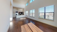 This well-appointed 1-bedroom, 1-bathroom residence offers a thoughtfully designed single-floor layout that balances modern aesthetics with functional living. The expansive living area immediately impresses with dramatically soaring ceilings that rise to clerestory windows, flooding the space with abundant natural light. Rich, dark-toned hardwood floors stretch across the main living area, complementing the neutral wall palette and creating a warm, inviting ambiance. A ceiling fan adds both style and comfort overhead, while a sliding glass door opens to an outdoor area, further enhancing the sense of openness. The open-concept design connects the living space seamlessly to the kitchen, which is outfitted with stainless steel appliances—including a refrigerator, range, and microwave—dark espresso cabinetry, granite countertops, a mosaic tile backsplash, and light tile flooring. A tall pantry cabinet provides generous storage. The bedroom is a serene retreat featuring plush carpeting, tall ceilings, and a sun-filled window with outdoor views. It includes access to a spacious walk-in closet with full wrap-around hanging rods. The bathroom is finished with large-format tile flooring, a granite-topped vanity with dark cabinetry, wall sconces, and a tiled soaking tub with a separate water closet.