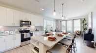 This single-floor residence is designed with a clean, contemporary aesthetic defined by neutral tones, wood-look flooring, and an abundance of natural light throughout. The open-concept kitchen is a functional centerpiece, featuring white shaker cabinetry extending to the ceiling, a subway tile backsplash, stainless steel appliances, and a generously sized island with granite countertops, an undermount sink, and bar seating. Pendant lighting above the island adds a stylish touch, while the layout flows seamlessly into the living and dining areas. The living room is bright and inviting, with large windows and sliding glass doors that open to a balcony offering outdoor views.

Both bedrooms are comfortably scaled, each equipped with a ceiling fan, large windows with blinds for light control, and walk-in closets with multi-level shelving and hanging rods. The bathrooms mirror the kitchen's design sensibility, showcasing dual-sink granite vanities with white cabinetry, large wall mirrors, glass-enclosed showers, and wood-look flooring. The primary bathroom also features built-in shelving for additional storage. Throughout the residence, the consistent use of granite, white finishes, and light flooring creates a cohesive and polished living environment.