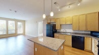 This well-appointed 2-bedroom, 2-bathroom unit in Denver, CO offers a thoughtfully designed single-level layout. The open-concept kitchen and living area serves as the heart of the home, featuring warm maple cabinetry, granite countertops, black appliances including a refrigerator, dishwasher, and range, and a peninsula island with pendant and track lighting overhead. Hardwood flooring runs throughout the main living areas, extending into the bright living room, which opens to a private outdoor balcony through large glass doors that fill the space with natural light.

Both bedrooms are carpeted and comfortable, each featuring windows with views of the surrounding neighborhood and ample wall space. The primary bedroom offers a generous footprint with natural light from dual windows. Both bathrooms are finished with tile flooring, wood cabinetry, granite-topped vanities, and stainless steel grab bars, reflecting an accessibility-conscious design. One bathroom includes a tiled walk-in shower with glass doors, while the other features a tub-shower combination.

A dedicated laundry room houses a full-size washer and dryer alongside built-in shelving and additional cabinet storage. Neutral warm tones and clean white trim throughout give the space a cohesive, move-in-ready feel.