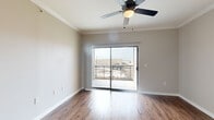 Located at 13100 W Bellfort Ave in Houston, TX, this two-bedroom, two-bathroom residence offers a well-organized single-floor layout designed for comfortable everyday living. The open-concept living area features warm wood-look hardwood flooring and neutral tones that create a bright, welcoming atmosphere. The kitchen is highlighted by a wide pass-through counter with granite countertops, a built-in sink, and stainless steel appliances, maintaining a seamless visual connection to the living space. The primary bedroom is generously sized, featuring crown molding, a ceiling fan with light, and a sliding glass door that opens to a private balcony with outdoor views. It includes a spacious walk-in closet with multi-tier wire shelving for ample storage. The second bedroom is carpeted, bathed in natural light from a large window with blinds, and is equipped with its own ceiling fan. Both bathrooms are finished consistently, showcasing granite-top vanities with white cabinetry, matte black hardware, tiled shower-tub combinations, and wood-look flooring. A dedicated laundry area with an included washer provides added convenience. Hallways connect each space efficiently, and the overall neutral color palette enhances the sense of openness throughout.