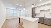 This well-designed one-bedroom, one-bathroom unit in Georgetown, Texas offers a thoughtfully laid-out single-floor plan with modern finishes throughout. The open-concept kitchen and living area serves as the heart of the home, anchored by a striking white quartz island illuminated by globe pendant lights. The kitchen features two-toned cabinetry — white upper cabinets paired with warm taupe lower cabinets — complemented by a classic subway tile backsplash and a full suite of stainless steel appliances, including a range, microwave, dishwasher, and refrigerator. Light wood-tone flooring flows seamlessly throughout the space, enhancing the bright, airy atmosphere created by recessed lighting and a ceiling fan. The living area benefits from natural light through large windows with blinds and provides access to the outdoors via a glass-panel door. The bedroom is a calm, neutral retreat with dual windows and a ceiling fan. The bathroom impresses with a large marble-style tiled soaking tub and shower surround, a white vanity with ample storage, and a framed mirror. A dedicated laundry room with a full-size washer and dryer and wire shelving rounds out this efficient and stylish home.
