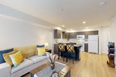 Located in Arlington, Washington, this efficiently designed one-bedroom, one-bathroom residence offers a thoughtful layout that maximizes every square foot. The open-concept living and kitchen area serves as the heart of the home, featuring light hardwood-style flooring that flows seamlessly throughout. The kitchen is outfitted with dark wood cabinetry, white countertops, white appliances including a refrigerator, electric range, over-the-range microwave, and dishwasher, along with recessed lighting that brightens the entire space. A movable island with a butcher block top adds both prep space and casual seating. The living area accommodates comfortable furnishings and benefits from natural light provided by a window and glass door that opens to a balcony. The bedroom offers a cozy retreat with a sliding-door closet, a window with natural light, and warm neutral tones. The bathroom includes a full tub and shower combination with multiple grab bars, reflecting accessible design considerations. A dedicated laundry area rounds out the functional layout. Clean white walls, consistent flooring, and recessed lighting throughout contribute to a bright, modern, and cohesive aesthetic.