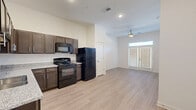 This one-bedroom, one-bathroom apartment at 610 S 29th St in Louisville, KY offers a thoughtfully designed single-floor layout that maximizes functionality. Light wood-style flooring runs throughout the main living areas, creating a clean, cohesive look. The open-concept kitchen and living area serves as the heart of the unit, featuring dark espresso cabinetry, granite-style countertops, a full suite of black appliances including a gas range, built-in microwave, dishwasher, and refrigerator — all complemented by a recessed sink. The living area is bright and airy, benefiting from natural light through large windows fitted with blinds and a ceiling fan overhead. The bedroom offers a comfortable footprint with a wide window that invites natural light, a ceiling fan, and direct access to additional spaces. Two closets provide generous storage throughout the unit. The bathroom is finished with large-format white tile flooring, a full tub-shower combination, a dark vanity with granite countertop, and a single sink. Additional conveniences include a dedicated laundry area and a utility room. The unit presents a modern, move-in-ready interior with a neutral color palette throughout.