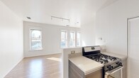 Located at 30 E Roosevelt Rd in Chicago's vibrant South Loop neighborhood, this single-floor unit offers a clean, modern design with an open and airy feel throughout. The living area is generously proportioned, featuring warm hardwood flooring, crisp white walls, and a bank of large windows that flood the space with natural light and frame views of the surrounding cityscape. Track lighting runs across the ceiling, providing flexible illumination throughout the main living space.

The kitchen is designed with functionality in mind, featuring a half-wall peninsula that separates it from the living area while maintaining an open connection. Dark wood-grain cabinetry adds contrast against the light countertops, and the kitchen is equipped with stainless steel appliances including a gas range, refrigerator, and microwave. Light tile flooring and a louvered pantry closet complete the practical layout.

The bathroom offers a refined finish with a granite-topped vanity, white shaker-style cabinetry, a large wall mirror with overhead lighting, and tile flooring. The space maintains a bright, clean aesthetic consistent with the rest of the unit.

Overall, this Chicago residence presents a well-appointed, contemporary living environment with an emphasis on natural light, open space, and modern finishes throughout.