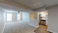 This single-story, three-bedroom, two-bathroom residence offers a thoughtfully designed open-concept layout with a clean, neutral palette throughout. The expansive living area is finished with plush wall-to-wall carpeting and features a ceiling fan with light kit, while multiple windows fitted with blinds allow natural light to fill the space. Structural beam details add architectural interest and help define the transition between the living and dining areas.

The kitchen is efficiently organized with white cabinetry accented by gold hardware, a white tile backsplash, and stainless steel appliances including a refrigerator, dishwasher, electric range with overhead ventilation hood, and built-in range hood. Wood-look flooring grounds the kitchen and extends into adjacent areas, creating a clear distinction from the carpeted living spaces. A pass-through counter connects the kitchen to the main living area.

Each of the three bedrooms offers carpeted flooring, ceiling fans, and windows that bring in natural light. The two bathrooms are finished with wood-look flooring, white vanities, and a tub-shower combination. One bathroom features a separate water closet and a walk-in closet, providing added functionality and storage.
