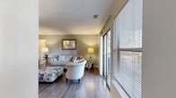 This single-floor, 2-bedroom, 2-bathroom residence offers a thoughtfully designed layout that makes efficient use of its space. The living room serves as the heart of the home, featuring warm hardwood-style flooring, neutral gray walls, and a large sliding glass door that floods the room with natural light and provides views of surrounding trees. The open flow connects seamlessly to a dedicated dining room, which features the same hardwood-style flooring, a pendant light fixture, and a wainscoting accent along the lower walls.

The galley-style kitchen is equipped with dark espresso cabinetry, light countertops, a mosaic tile backsplash, and black appliances including a gas range. A pantry off the kitchen provides additional storage. The primary bedroom is a comfortable retreat with plush carpet, soft neutral tones, and a walk-in closet. The second bedroom also features carpet flooring and its own closet. Both bathrooms are clean and functional, with the full bath offering a shower-tub combination. Additional storage is provided by two closets and a hallway connecting the rooms. The entrance provides a welcoming transition into the home's cohesive, neutral-toned interior.