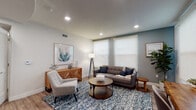 Located at 965 Schooner Dr in Ventura, California, this single-story residence offers a thoughtfully designed layout with a cohesive coastal aesthetic carried throughout. Light wood-tone flooring flows continuously across the living spaces, complementing a neutral color palette accented by muted blues and warm wood tones.

The living room is bright and welcoming, with recessed lighting and roller shade windows that allow for adjustable natural light. An accent wall in a soft blue-gray tone adds visual depth to the space, which is well-proportioned for comfortable everyday living.

The kitchen is a standout feature, showcasing rich espresso-toned cabinetry extending to the ceiling, light quartz countertops, a subway tile backsplash, and a full suite of stainless steel appliances including a gas range, microwave, dishwasher, and side-by-side refrigerator. A tray ceiling detail adds architectural interest overhead.

The bedroom is generously sized with recessed lighting, a tray ceiling, and a window fitted with a roller shade. It connects to a walk-in closet outfitted with multi-tier shelving and hanging rods, offering ample storage. The bathroom features dark cabinetry with a white countertop, an undermount sink, and a large vanity mirror.