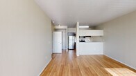 Located at 390 E Main St in Hillsboro, Oregon, this well-appointed 2-bedroom, 2-bathroom residence offers a thoughtfully designed single-floor layout. The open-concept living and dining area is bright and welcoming, featuring light wood-style flooring, neutral wall tones, and large windows with an exterior door that floods the space with natural light and provides outdoor views. The kitchen is efficiently designed with rich dark cabinetry, stainless steel appliances including a refrigerator, electric range, and microwave, light countertops, and a peninsula that opens to the main living area. Both bedrooms are generously proportioned and carpeted, with ample natural light streaming through blinds-fitted windows. The spacious primary bedroom offers a comfortable, quiet retreat. Both bathrooms echo the kitchen's dark cabinetry aesthetic, featuring wood-style flooring, clean white countertops, and tub/shower combinations. A dedicated in-unit laundry area houses a full-size washer and dryer with overhead shelving for added storage convenience. A separate closet provides additional storage. The unit's clean, neutral palette and consistent finishes throughout create a cohesive and move-in-ready living environment.
