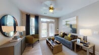 This well-appointed single-floor residence offers a thoughtfully designed layout that balances comfort and modern style. The living room serves as the heart of the home, featuring light wood-style flooring, a ceiling fan, and French doors with transom windows that invite abundant natural light and provide access to an outdoor area. Elegant dark curtains frame the windows, adding a refined contrast to the neutral walls, while a large abstract artwork anchors the space above a plush gray sofa with olive and yellow accent pillows.

The kitchen is outfitted with crisp white shaker-style cabinetry, granite countertops, a white subway tile backsplash, and a full suite of stainless steel appliances including a refrigerator, electric range, and built-in microwave. Light wood flooring flows seamlessly throughout the space, reinforcing a cohesive aesthetic.

The bedroom is a serene retreat with soft gray walls, a ceiling fan, and a large window dressed with white curtains that bathe the room in natural light. The bathroom features a full tub-shower combination with white subway tile surround and light wood-look flooring. A dedicated in-unit laundry room with a full-size Whirlpool washer and dryer rounds out this functional and stylish residence.
