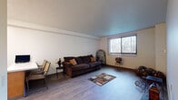 Located at 125 E 156th St in Cleveland, Ohio, this single-floor unit offers a well-organized layout with clearly defined living, sleeping, and functional spaces throughout. The living room serves as the central gathering area, featuring light hardwood-style flooring, neutral walls, and a large window dressed with vertical blinds that allows natural light to fill the room and provides views of the surrounding neighborhood. The open feel of the living area is enhanced by clean lines and a modest but comfortable layout. The kitchen is efficiently designed with warm oak cabinetry offering ample storage, a dual-basin sink, and a white electric range. A built-in dining area with a countertop table and seating makes the kitchen a practical space for everyday meals. The unit includes two bedrooms, both finished with hardwood-style flooring and neutral walls. The primary bedroom features a built-in closet with sliding doors and direct access to the bathroom, while the secondary bedroom offers a window for natural light and additional living flexibility. The full bathroom is equipped with a single-sink oak vanity with an integrated mirror, a toilet, and a shower-tub combination. Throughout the unit, consistent flooring and a neutral color palette create a cohesive and functional living environment.