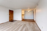 Located at 300 RT-291 S in Lee's Summit, Missouri, this single-floor unit offers a practical and functional layout spread across several connected living spaces. The entry opens into a generously sized living area finished with neutral-toned carpet and a textured ceiling, providing a comfortable and open feel. Clean white walls and wood-tone baseboards run throughout, contributing to a cohesive interior aesthetic.

The living area flows seamlessly into the kitchen and dining space, which features wood-look flooring, light blue accent walls, and a ceiling fan with integrated lighting. The kitchen is equipped with white cabinetry, a countertop sink, and ample overhead storage, complemented by an included white range.

The bedroom is a well-proportioned room with plush carpeting, a ceiling fan, and a built-in closet, offering practical everyday storage. A hallway connects the bedroom to the bathroom, which includes a full tub with white tile surround, wood-look flooring, and dark wood-toned door frames that add a warm contrast to the lighter finishes throughout.

Ceiling fans are present in multiple rooms, supporting year-round comfort. The overall layout is efficient and accessible, making this single-level space well-suited for straightforward, comfortable living in Lee's Summit.