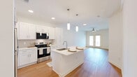 Located at 8456 Golden Hawk Dr W in Millington, TN, this single-floor, one-bedroom, one-bathroom residence offers a thoughtfully designed open-concept layout with consistent light wood flooring throughout. The kitchen serves as the heart of the home, anchored by a central island with a white quartz countertop, an undermount sink, and pendant lighting overhead. White shaker-style cabinetry lines the walls, complemented by a full suite of stainless steel appliances including a refrigerator, electric range with microwave, and dishwasher. The kitchen flows seamlessly into the living area, which is bathed in natural light from double French doors and a ceiling fan. The bedroom is a comfortable, well-proportioned room with warm wood flooring, crisp white walls, and a large window fitted with blinds offering views of the surrounding neighborhood. The bathroom features a clean, modern vanity with a white countertop, undermount sink, and a large mirror, accompanied by wood flooring and ample storage. A dedicated laundry room houses a full-size Whirlpool washer and dryer with overhead wire shelving for additional storage. A closet rounds out the functional layout of this move-in-ready residence.