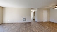 Located in Aloha, Oregon, this 2-bedroom, 2-bathroom apartment offers a functional and well-appointed single-floor layout. The open combined living and dining area is finished with durable wood-look flooring and features a wall-mounted heater unit and a textured ceiling. A sliding glass door fills the dining area with natural light and provides direct access to a private patio with outdoor views. The kitchen is outfitted with white cabinetry, stone-look countertops, a stainless steel sink, and a window that brings in additional natural light. Both bedrooms are carpeted and finished in warm neutral tones. The primary bedroom is generously sized and connects to a walk-in closet with built-in shelving and hanging rods. The second bedroom also features a walk-in closet and a window with natural light. In total, the unit offers five closets, providing excellent storage throughout. Each bathroom features wood-look flooring, a white vanity with stone-look countertops, and clean, neutral finishes. A dedicated in-unit laundry area adds everyday convenience. A connecting hallway links the common areas to the private bedrooms and bathrooms, creating a practical and cohesive flow throughout the home.