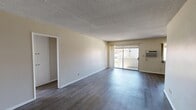 Located at 7050 Jordan Ave in Canoga Park, CA, this one-bedroom, one-bathroom unit offers a practical and comfortable single-floor layout. The open-concept living and dining area is a welcoming space, featuring dark hardwood-style flooring, textured ceilings, and neutral-toned walls that create a clean, bright atmosphere. A wall-mounted AC unit keeps the space climate-controlled, while a sliding glass door opens to an outdoor area, allowing natural light to pour in and providing direct access to the exterior.

The kitchen is efficiently designed in a galley-style configuration, featuring warm wood cabinetry, tile countertops, a white electric range, and a built-in microwave. Open shelving adds additional storage and accessibility. A ceiling fan sits above the adjoining hallway, enhancing airflow throughout the space.

The bedroom is a generously sized retreat with hardwood-style flooring, a wall-mounted AC unit, and a tall window that brings in natural light. It includes a built-in sliding closet with overhead storage cabinetry, maximizing organization. Two additional closets throughout the unit provide further storage options.

The bathroom is clean and functional, equipped with a shower-tub combo featuring sliding frosted glass doors, a vanity, and light flooring. A hallway connects all rooms cohesively, completing this well-organized and efficiently laid-out home.