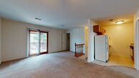 This residence offers a practical and comfortable layout spread across its floor plan, with a staircase serving as a central architectural element connecting the levels. The open living area is carpeted and bathed in natural light from a large sliding glass door that leads to an outdoor balcony, offering views of surrounding greenery. Adjacent to the living space, the kitchen is equipped with warm-toned wooden cabinetry, tile flooring, a white refrigerator, an electric range, and an over-the-range microwave, providing all the essentials for everyday cooking.

The bedrooms are generously proportioned, each featuring plush carpeting, ceiling fans with integrated light fixtures, and large windows that invite natural light. One bedroom includes an en-suite bathroom, while another benefits from dual closets with built-in hanging rods, offering exceptional storage capacity. The bathroom is clean and functional, featuring a full-sized soaking tub and shower combination with a crisp white surround. Throughout the home, a neutral color palette of whites and beiges creates a bright, cohesive, and move-in-ready atmosphere.