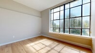 Located at 221 N Central Ave in Fairborn, Ohio, this single-floor, 3-bedroom, 1-bathroom unit offers a clean and modern interior with a cohesive design throughout. Warm-toned hardwood flooring runs continuously across all rooms, complementing the neutral gray walls and crisp white trim that define the space's contemporary aesthetic.

The primary bedroom is the largest of the three, featuring notably high ceilings that amplify the sense of space, a built-in sliding closet, and ample natural light. The second bedroom is a standout, boasting a striking floor-to-ceiling industrial-style grid window that floods the room with sunlight and offers views of the surrounding greenery. The third bedroom also benefits from elevated ceilings and a clerestory-style horizontal window positioned high on the wall, providing light while maintaining privacy.

The single full bathroom is efficiently designed, featuring a bathtub with shower, toilet, and wood-look flooring consistent with the rest of the unit. A connecting hallway links all rooms in a practical layout. Throughout the unit, ceiling-mounted HVAC vents ensure climate control, and the overall design emphasizes clean lines, abundant natural light, and a bright, move-in ready atmosphere.