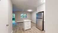 Located at 65 Paisley Blvd W in Mississauga, Ontario, this thoughtfully updated one-bedroom, one-bathroom unit offers a clean, modern aesthetic throughout. The open-concept kitchen and living area forms the heart of the space, featuring light hardwood-style flooring, neutral walls, and a central kitchen island with built-in storage. The kitchen is well-appointed with white shaker cabinetry extending to the ceiling, a full suite of stainless steel appliances including a refrigerator, dishwasher, electric range, and over-the-range microwave, plus a subway tile backsplash and a double-basin sink. The living area is bright and airy, bathed in natural light from large windows and a sliding glass door that opens onto a private balcony overlooking lush greenery. A baseboard heating system runs along the exterior wall. The bedroom is a calm, carpeted retreat featuring double closet doors and a second closet nearby, providing generous storage. The full bathroom is finished in crisp white tones, complete with a white vanity, quartz countertop, a full soaker tub with tiled surround, and a large mirror. The unit's cohesive, renovated finishes and greenery views create a bright, comfortable living environment.