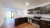 This contemporary 960 square foot apartment in Madison, WI, offers a harmonious blend of style and functionality. The open-concept design seamlessly integrates the living room and kitchen, creating a spacious feel. The kitchen boasts dark wood cabinetry, stainless steel appliances, and elegant granite countertops, complemented by stylish pendant lighting.

Hardwood floors in the main living areas contrast beautifully with plush carpeting in the bedrooms, providing comfort underfoot. Large windows allow natural light to flood the space, enhancing the bright and airy ambiance. The primary bedroom, measuring 180 square feet, offers ample space for relaxation.

Both bathrooms feature modern fixtures, including a tub-shower combination with a curved shower rod in one, and a spacious vanity with plenty of storage in the other. The apartment also includes a dedicated laundry area with in-unit washer and dryer.

Storage is plentiful, with a walk-in closet and additional built-in closet space. The neutral color palette throughout allows for easy personalization. Recessed lighting adds to the contemporary feel, while the overall design prioritizes both aesthetics and practicality in this well-appointed urban dwelling.