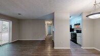 This well-appointed 2-bedroom, 1-bathroom single-floor residence offers a thoughtfully designed layout across a comfortable footprint. The living room serves as a central gathering space, highlighted by a classic white brick fireplace and a large sliding glass door dressed with vertical blinds, allowing natural light to pour in while providing access to the outdoors. Dark hardwood-style flooring extends throughout the main living areas, lending warmth and continuity to the space.

Adjacent to the living room, the dining area features warm hardwood-style flooring and a pendant light fixture, flowing seamlessly into the galley-style kitchen. The kitchen is equipped with white cabinetry, light countertops, a tile backsplash, a double sink, and black appliances including a range and refrigerator, with direct access to the utility room beyond.

The primary bedroom is generously sized and features soft carpeting and two closets with built-in hanging rods, offering ample storage. The second bedroom is also carpeted and well-proportioned, serviced by the shared full bathroom, which includes a single vanity with storage, a tub-shower combination, and hardwood-style flooring. A hallway, entrance area, and dedicated closet complete this efficiently organized home. Textured ceilings are present throughout.