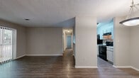 This well-appointed 2-bedroom, 1-bathroom single-floor residence offers a thoughtfully designed layout across a comfortable footprint. The living room serves as a central gathering space, highlighted by a classic white brick fireplace and a large sliding glass door dressed with vertical blinds, allowing natural light to pour in while providing access to the outdoors. Dark hardwood-style flooring extends throughout the main living areas, lending warmth and continuity to the space.

Adjacent to the living room, the dining area features warm hardwood-style flooring and a pendant light fixture, flowing seamlessly into the galley-style kitchen. The kitchen is equipped with white cabinetry, light countertops, a tile backsplash, a double sink, and black appliances including a range and refrigerator, with direct access to the utility room beyond.

The primary bedroom is generously sized and features soft carpeting and two closets with built-in hanging rods, offering ample storage. The second bedroom is also carpeted and well-proportioned, serviced by the shared full bathroom, which includes a single vanity with storage, a tub-shower combination, and hardwood-style flooring. A hallway, entrance area, and dedicated closet complete this efficiently organized home. Textured ceilings are present throughout.