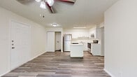 Located at 3631 Callaghan Road in San Antonio, TX, this two-bedroom, two-bathroom residence offers a thoughtfully arranged single-floor layout. Wood-look plank flooring runs throughout the home, providing a cohesive and clean aesthetic from room to room.

The open-concept living and dining area is bright and welcoming, with a ceiling fan overhead and a textured ceiling. The kitchen flows seamlessly into this shared space and is well-equipped with white cabinetry, stainless steel appliances including a refrigerator, electric range, and dishwasher, a kitchen island, and ample counter space — ideal for both cooking and casual dining.

The primary bedroom is a comfortable size and features a ceiling fan and sliding glass doors that open directly onto a private balcony with lush tree views, bringing in natural light and a connection to the outdoors. The second bedroom also benefits from natural light through a large window with blinds.

Each bedroom is served by its own bathroom, one of which is combined with in-unit laundry access. Both bathrooms feature clean, minimal finishes. Additional storage is provided through closets accessible from the hallway. The balcony offers a pleasant outdoor retreat surrounded by greenery, completing this functional and well-appointed San Antonio residence.