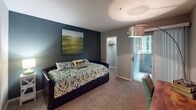 This single-floor residence is thoughtfully designed with a neutral, contemporary color palette of warm grays and taupe tones throughout. Dark hardwood-style flooring flows through the main living areas, creating a cohesive and polished look. The living room offers a comfortable, open feel, accented by a textured ceiling and direct sightlines toward the kitchen and hallway.

The kitchen is efficiently laid out with white shaker-style cabinetry, dark granite-look countertops, black appliances including an electric range, and a stainless steel sink. A breakfast bar with seating connects the kitchen to the dining area, making it ideal for casual meals.

The primary bedroom features plush carpeting, a bold navy accent wall, a window for natural light, and direct access to an en-suite bathroom. The en-suite includes white cabinetry, dark countertops, a large mirror, and a shower-tub combination. The second bedroom also features carpeting, an accent wall, a closet, and access to natural light. A second full bathroom with a shower-tub combo serves this room. A dedicated laundry room with side-by-side washer and dryer and built-in shelving completes the unit.