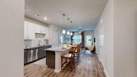 Located at 5697 SW 49th Rd in Ocala, Florida, this thoughtfully designed single-story residence offers two bedrooms and two bathrooms within a comfortable and modern floor plan. The open-concept kitchen is a standout feature, showcasing white upper cabinetry, dark lower cabinets, stainless steel appliances, granite countertops, a subway tile backsplash, and a large island with pendant lighting and bar seating — ideal for both cooking and entertaining. Wood-look flooring flows seamlessly from the kitchen into the bright living room, which is filled with natural light from large windows dressed with blinds and elegant drapery. The primary bedroom offers a generous footprint, plush carpeting, a ceiling fan, and a warm accent wall, creating a relaxing retreat. The second bedroom is equally well-appointed with carpeting and ceiling fan. Both bathrooms feature granite vanities and wood-look tile flooring, with the full bath including a tub-shower combination. A dedicated in-unit laundry room adds everyday convenience. Two closets provide ample storage throughout. The overall aesthetic is clean and contemporary, with neutral tones and modern finishes creating a cohesive and inviting atmosphere throughout the home.